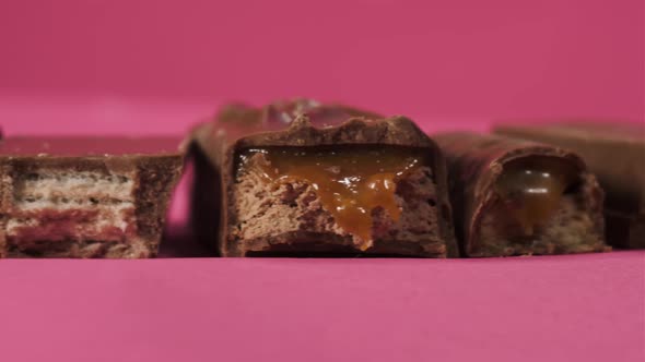 Tasty Bitten Chocolate Candy Bars Slider Move on Pink Background Isolate. Unhealthy Food for