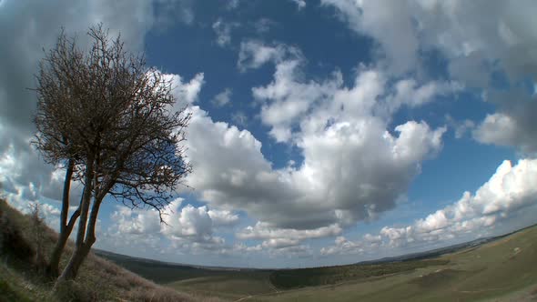 Time lapse of clouds over rural landscape with green hills