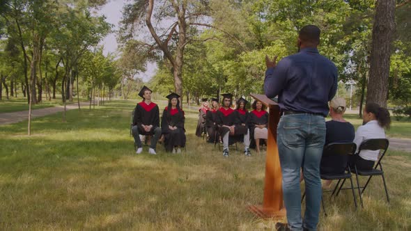Diverse Multiracial Graduates Applauding to College Dean Speech at Graduation Ceremony