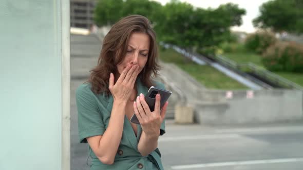 Sad Woman in a Turquoise Dress in the City. An Interesting Lady Holds a Mobile Phone in Her Hands