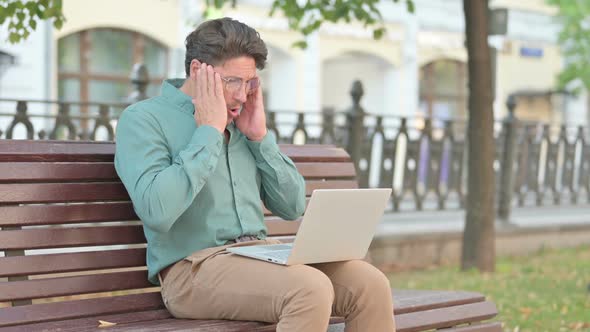 Man Feeling Shocked while using Laptop on Bench