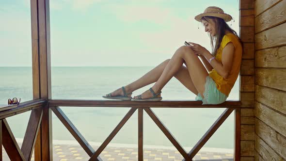 Side View Woman in Hat at Beach with Laptop Using Smartphone Online Chatting Browsing on Internet