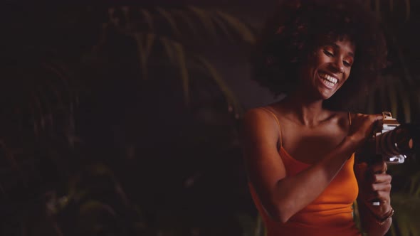 Woman With Afro Hair In Orange Dress Using Vintage 8Mm Camera