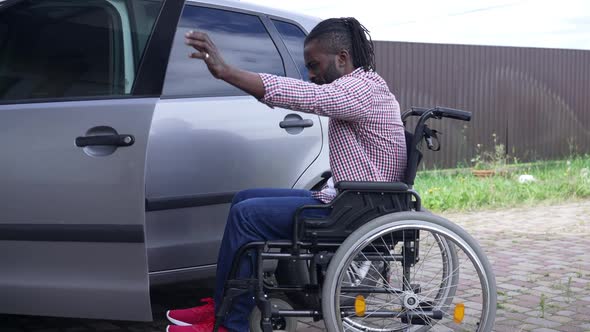 Disabled African American Man Riding Wheelchair to Car Making Effort Sitting on Driver's Seat