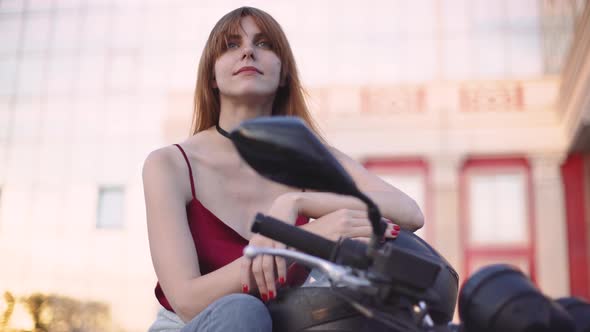 Beautiful Young Redhaired Woman Motorcyclist with Her Motorcycle and Helmet