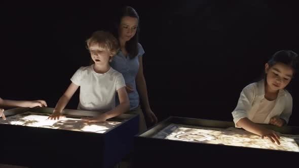 Woman Giving Advice to Kids Making Sand Animation