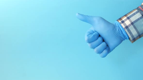 Hand in Medical Gloves Showing a Thumbup on Blue Background