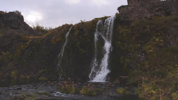 Waterfall From Steep Cliff Into River