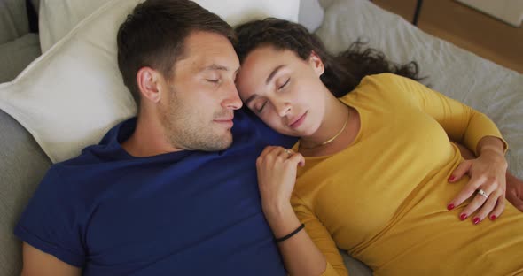 Happy caucasian couple resting and taking a nap in bed