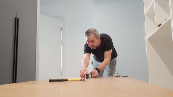 A Man Hammers Nails Into the Back of a Closet