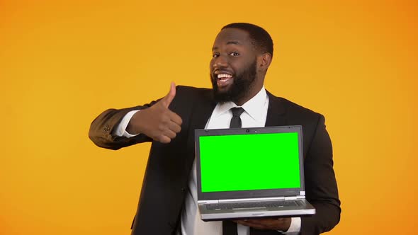 Joyful Afro-American Businessman Showing Prekeyed Laptop and Thumbs-Up Gesture
