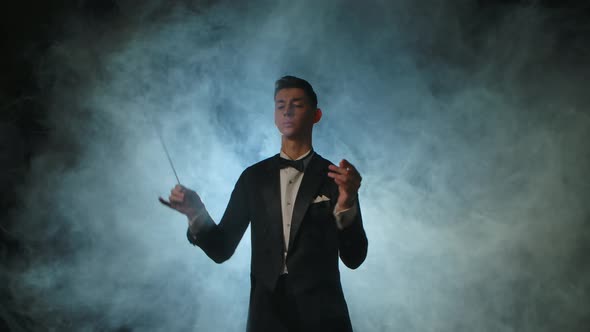 An Orchestra Leader Wearing Suit Using the Conducting Baton to Synchronize the Musicians
