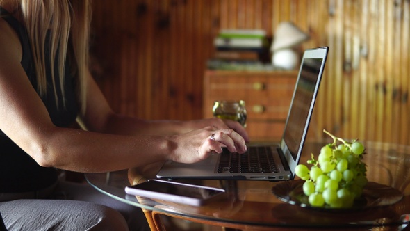 Beautiful blonde girl typing on a laptop