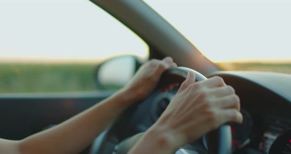 Close Up Female Hands Driving Car Outside City