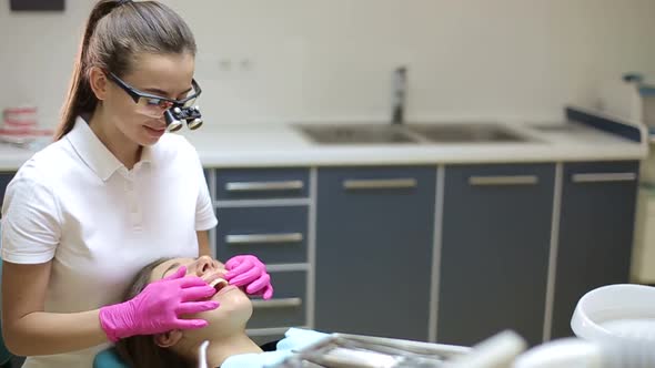Dentist treating teeth to woman patient in clinic.