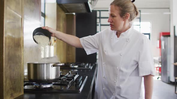 Caucasian female chef pouring salt into boiling water