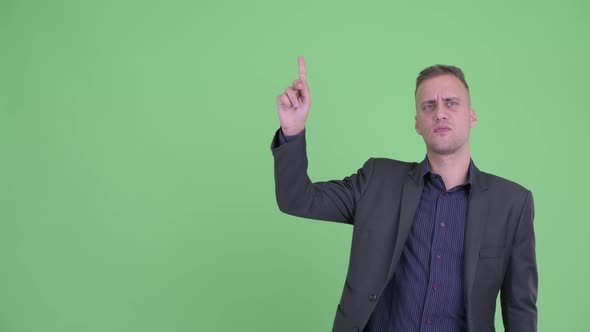 Stressed Businessman in Suit Talking While Pointing Up