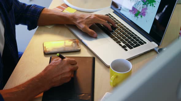 Man using graphic tablet while working on laptop 4k