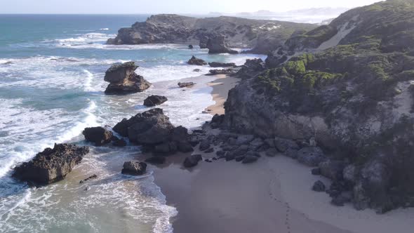 Aerial View of Man Seen Walking Along Beautiful Coastline