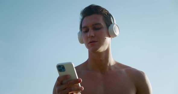 Happy Athletic Sporty Man Using Smartphone with Wireless Headphones Enjoying Listening to Music