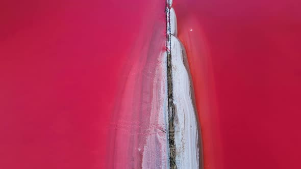 Epic Drone Flight Over Beautiful Pink Salt Lake with Deep Colorful Calm Water Surface and Small