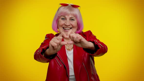 Smiling Senior Woman Makes Heart Gesture Demonstrates Love Sign Expresses Good Feelings and Sympathy