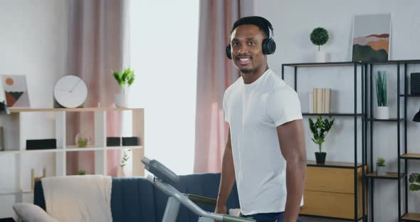 Black-Skinned Guy in Headphones Looking at Camera while Walking on Running Track