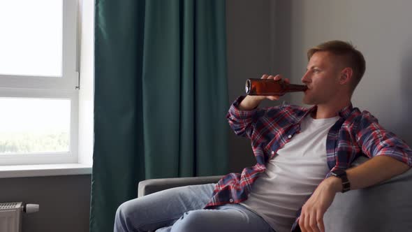 A Young Man Drinking Beer While Sitting on the Couch