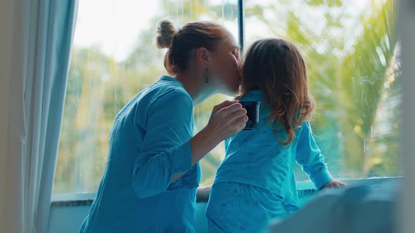 Morning at the bedroom. Mother and kid enjoy early morning time together and watch in the window