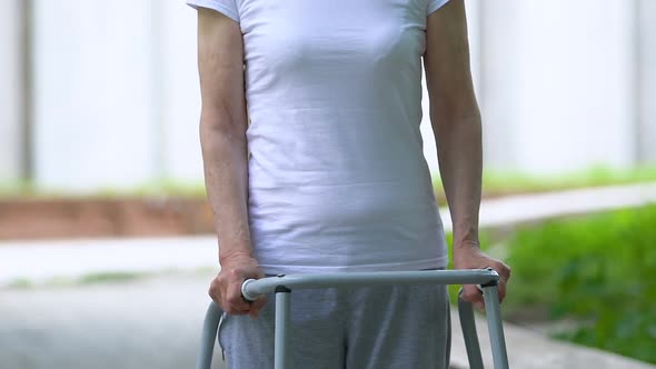 Upset Senior Woman With Walking Frame Looking at Camera Outdoors, Joint Trauma