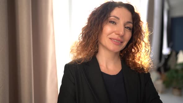 Business Woman or Teacher in Black Business Suit Sunny Portrait of a Curly Girl Opposite the Window