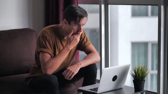Afraid Man is Unpleasantly Surprised and Shocked By the Bad News Seen on the Laptop Screen