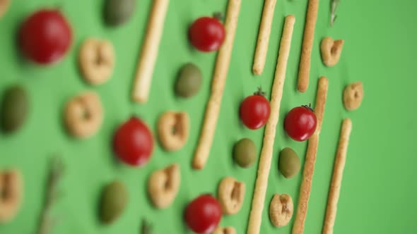 Vertical video: pattern of italian pastries, italian bread sticks, olives, cherry tomatoes, rosemary