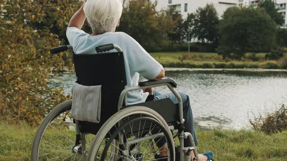 Senior Disabled Woman Sitting in the Wheelchair Enjoying Autumn Breeze Near the River