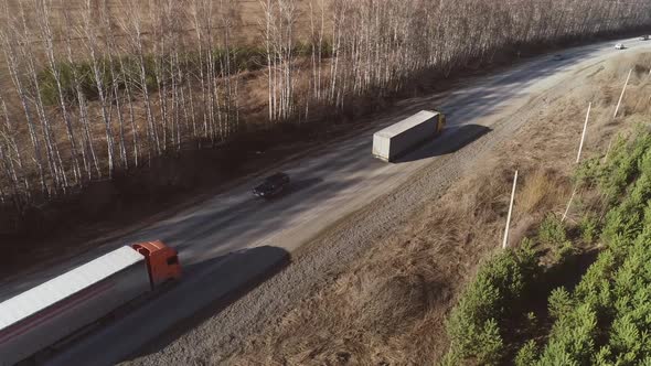 Aerial view of three trucks and cars are driving along the spring road 16