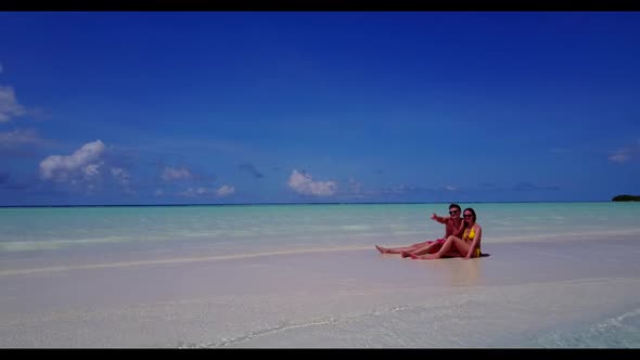 Guy and girl happy together on luxury tourist beach vacation by turquoise sea with white sandy backg