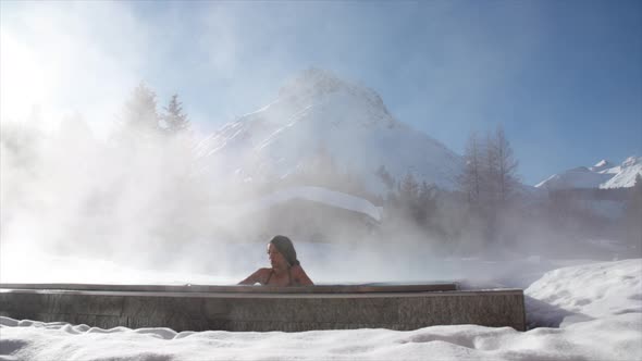 A woman relaxes in a hot tub jacuzzi at a spa.