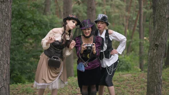 Zoom Out Three Happy Beautiful Women in Steampunk Costumes Watching Photos on Camera Smiling Talking