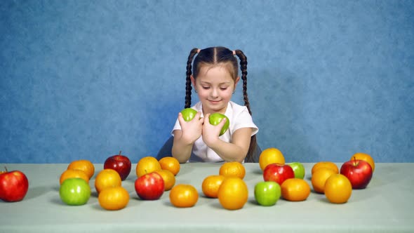 Smiling little girl holds two green apples at home