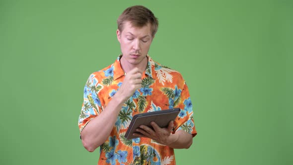 Young Handsome Tourist Man Using Digital Tablet and Thinking