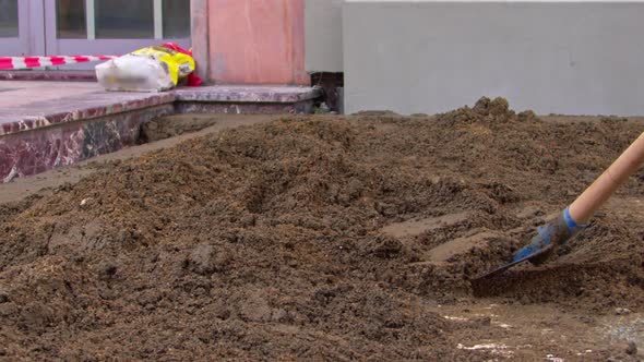 A Builder Shovels Sand In The Work Area 2