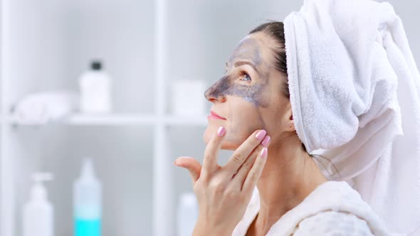 Young Woman with White Towel on Her Head Smearing Cosmetic Mask on Face