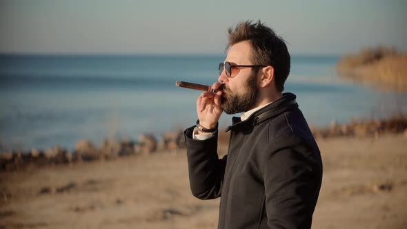 Relaxing Businessman In Sunglasses Smoke Cigar. Confident Well-Dressed Man Smoking.