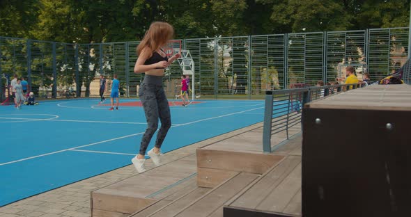 Sport Girl is Performing Squats with Jumping on the Step