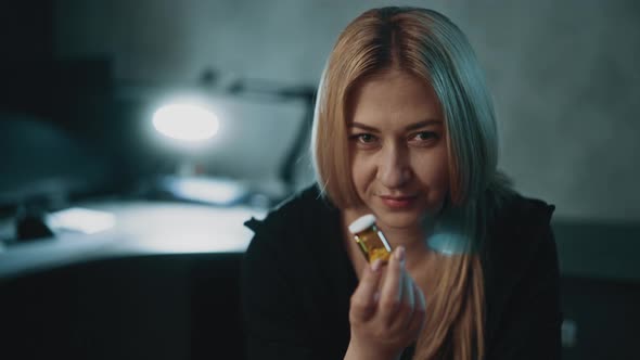 Woman with Inscrutable Smile Holds Small Pill Bottle in Room