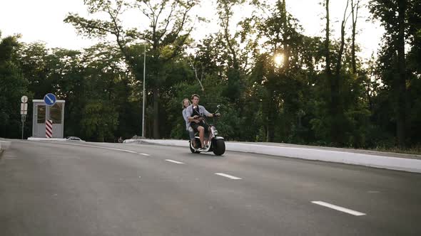 Two Friendscouple are Riding on an Electro Minibike By Road