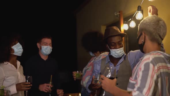 Happy multiracial friends having fun dancing and celebrate holidays while wearing face mask