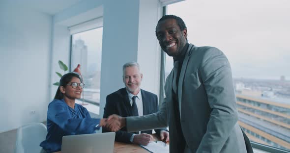 African candidate shake hands with recruiter and smile to the camera