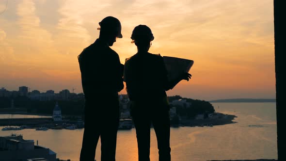 Workers Standing on a Sunset Background Back View
