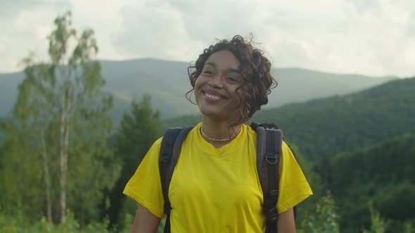 Portrait of Happy Charming African Woman Hiker Smiling Over Scenic Mountain Landscape at Sunset